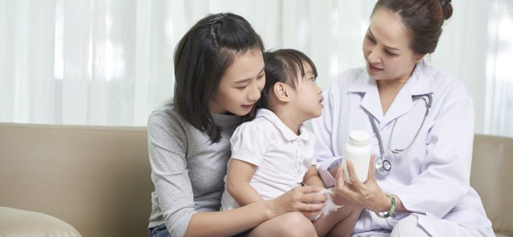 Pediatrician showing prescribed medicine mother and her little daughter