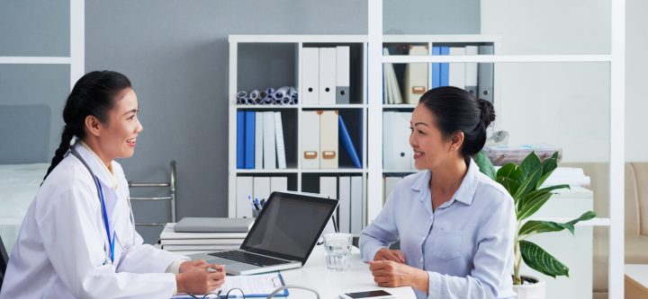 Smiling Asian doctor consulting senior female patient
