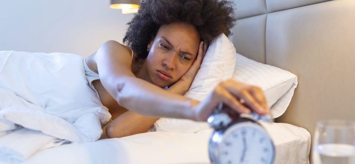 Wake up of an asleep girl stopping alarm clock on the bed in the morning. woman sleeping and wake up to turn off the alarm clock in the morning